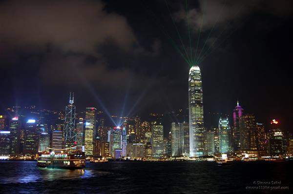 Illuminated Hong Kong skyscrapers with light show, ferry crossing Victoria Harbour