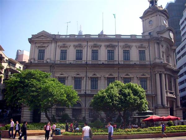 Macau's colonial Post Office building facing Senado Square, people strolling under leafy trees