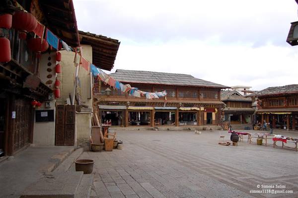 Stone square with Tibetan wooden houses, prayer flags and red lanterns