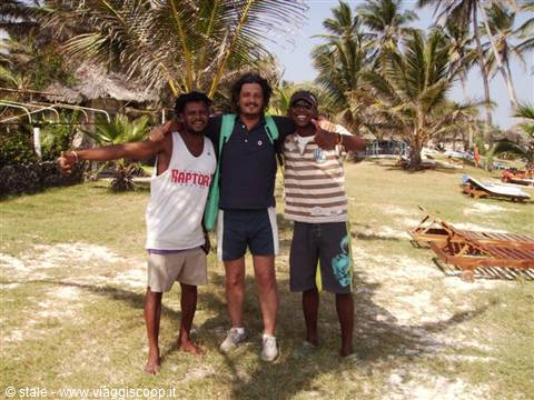 Three friends hugging on beach with palms, wooden sun loungers and sand