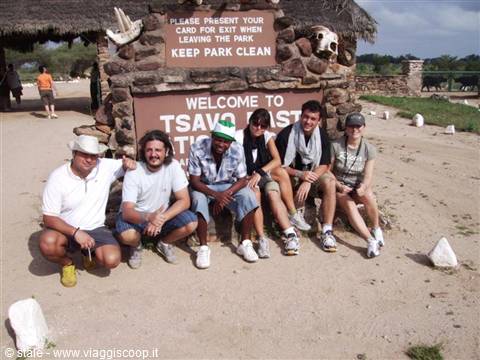 Tourist group crouching in front of the Tsavo East park entrance sign