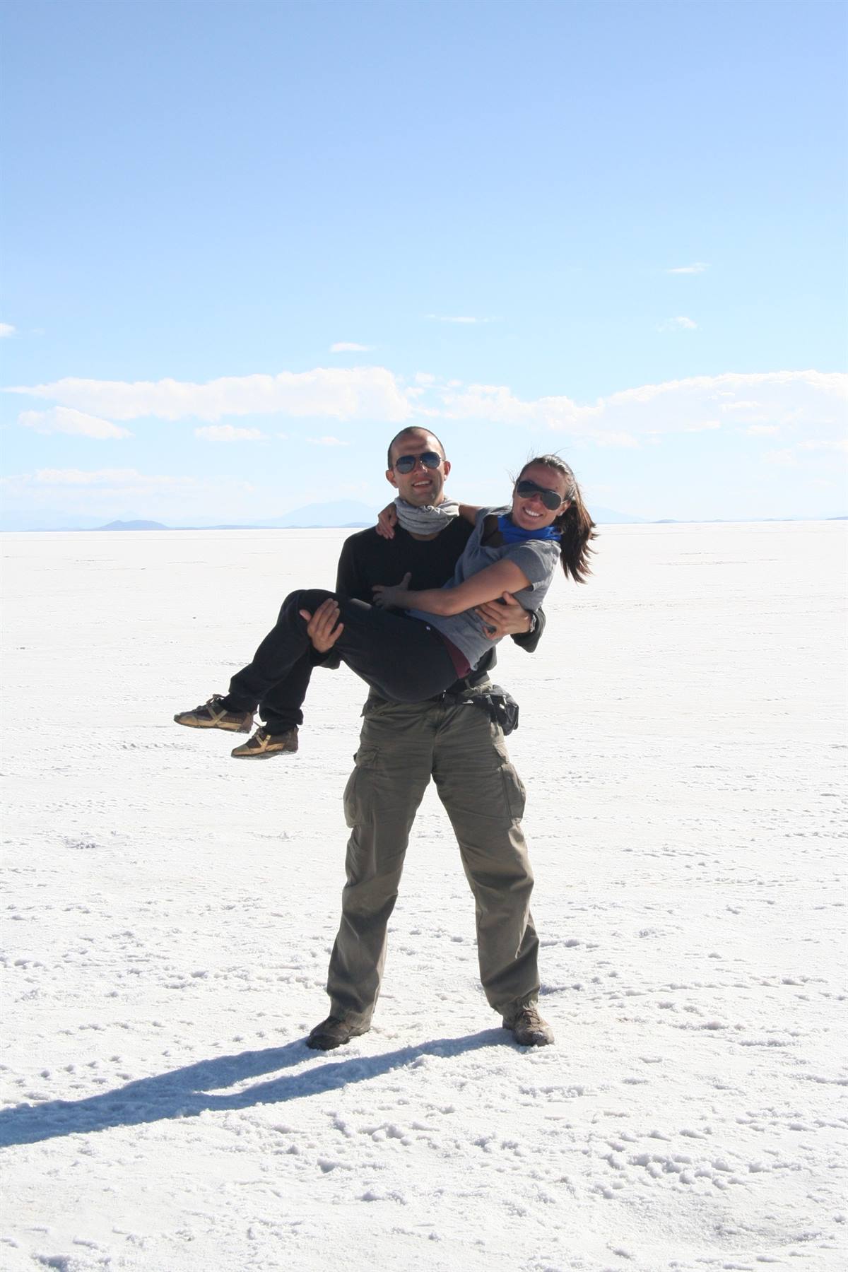 Uomo solleva una donna ridendo sul bianco sale di Salar de Uyuni