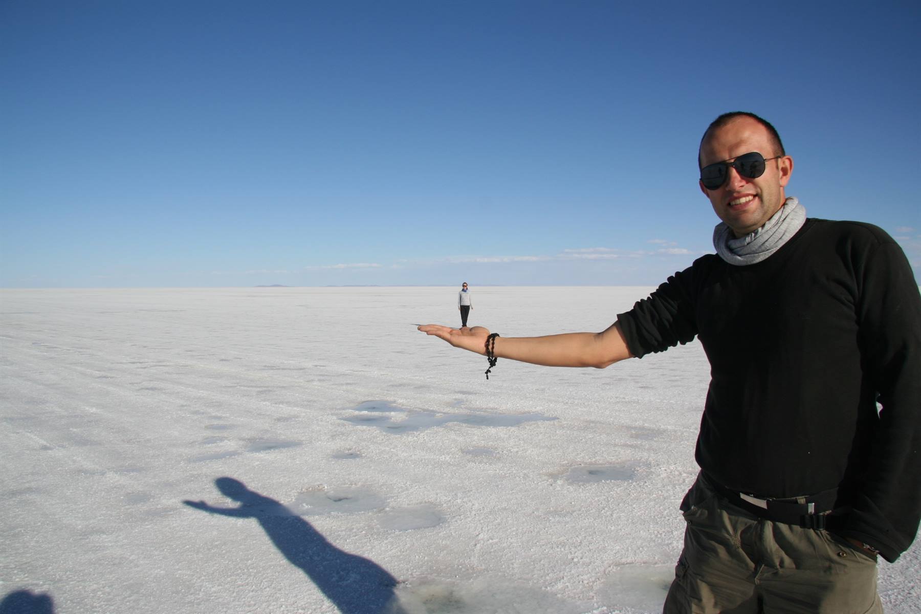 Uomo con occhiali da sole fa illusione ottica su un turista, Salar de Uyuni