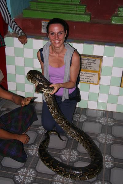 Smiling woman holding a large python inside a tiled temple