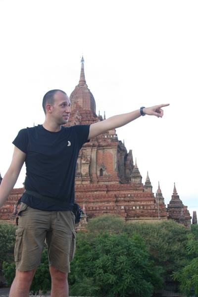 Tourist pointing at a brick temple among the trees, Bagan