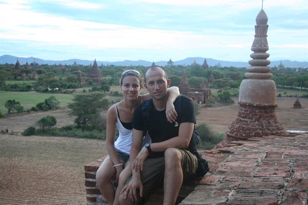 Couple sitting on brick terrace surrounded by pagodas and stupas, Bagan