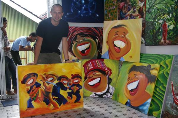 Visitor among colorful paintings of laughing faces in an art shop