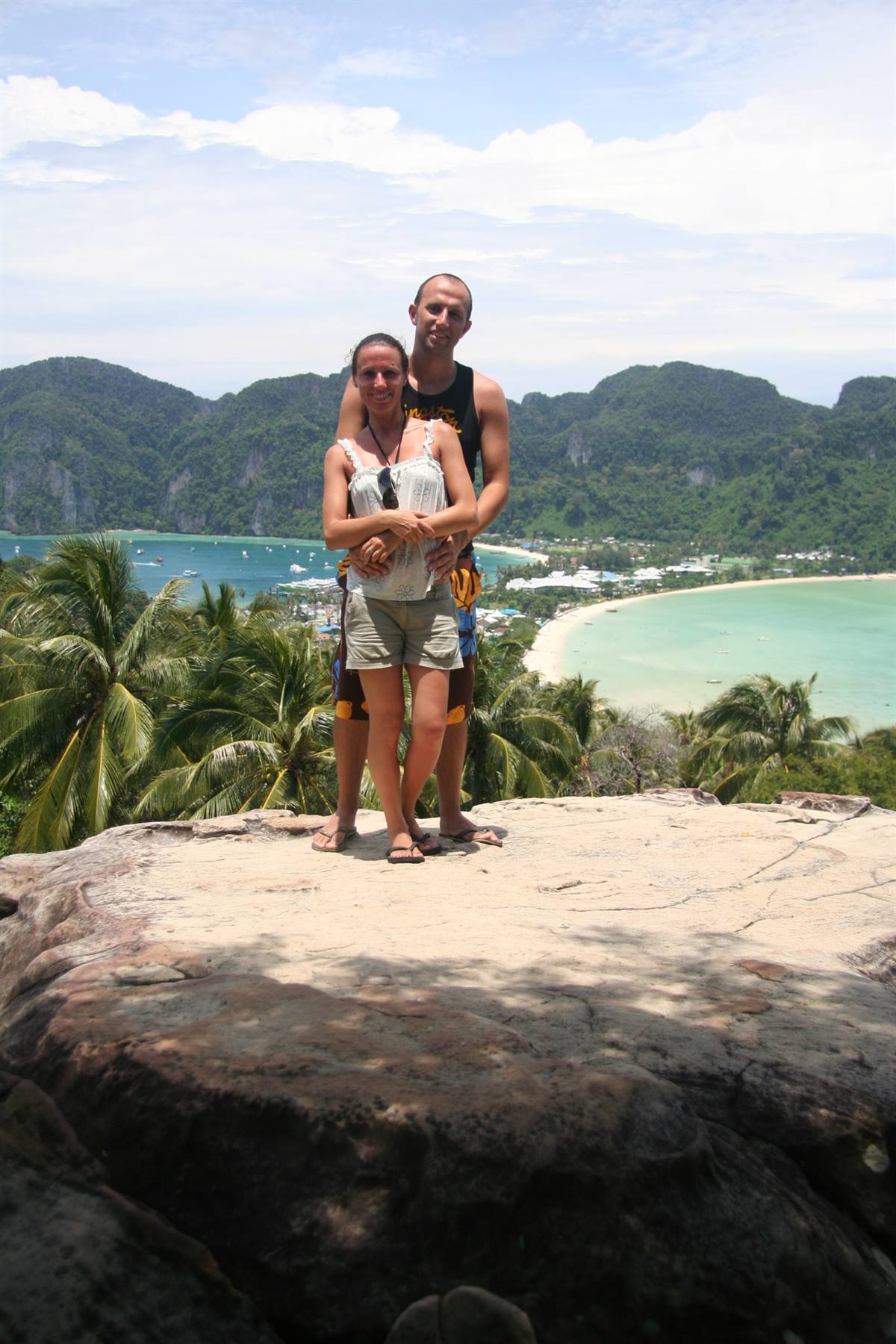 Coppia abbracciata sulla roccia del viewpoint, golfi turchesi e palme a Ko Phi Phi