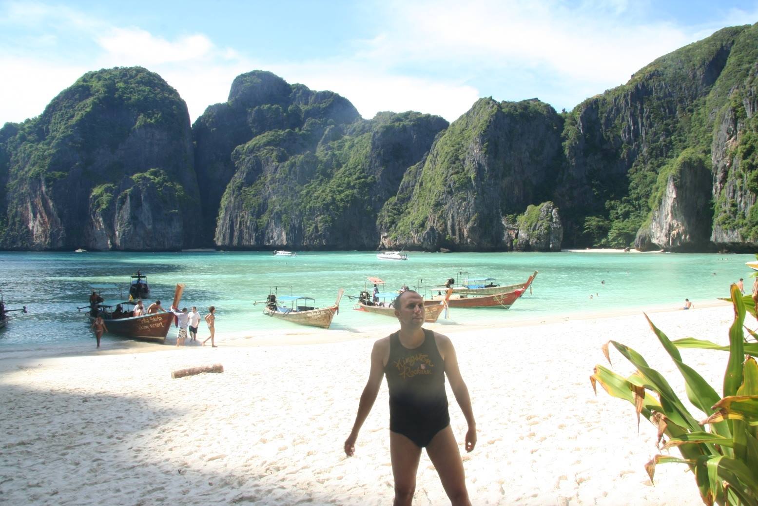 Turista in costume sulla spiaggia di Maya Bay, longtail ormeggiate tra falesse calcaree