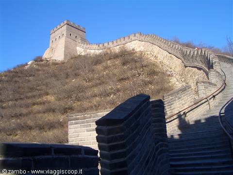 The Great Wall climbs steeply among grey stone towers under blue sky