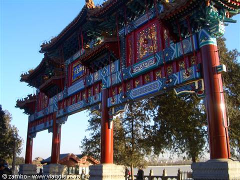 Ornate red and blue wooden gateway with golden roofs, lakeside park