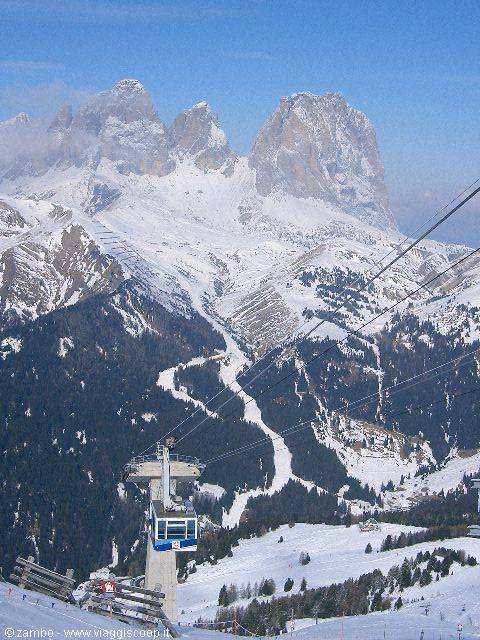 Chairlift above snowy ski slopes with the Sella massif in the background