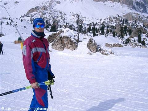 Skier in blue and red suit with poles on snowy Dolomites slopes