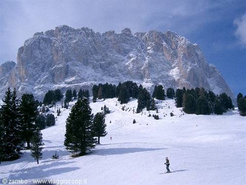 Skier on snow beneath the rocky Dolomites cliffs