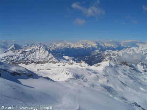 Snow-covered peaks and ski slopes under blue sky, Stelvio Pass