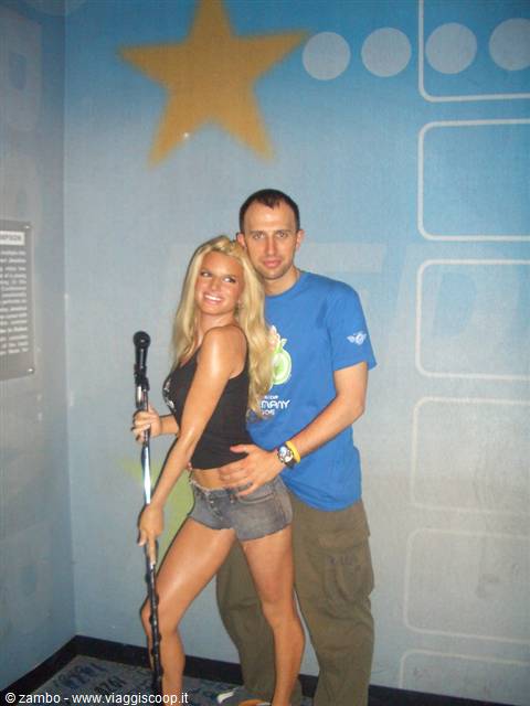 Tourist posing beside a blonde wax figure holding a microphone, blue star wall