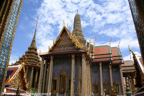 Golden spires and stupas of Bangkok's Grand Palace under a cloudy sky