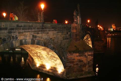 Charles Bridge at night, lights beneath stone arches over the Vltava, Prague