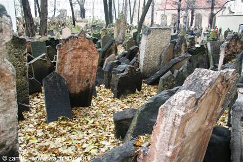 Prague's Old Jewish Cemetery, crowded tilted stone tombstones among fallen autumn leaves