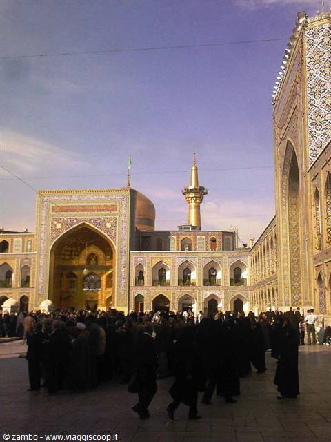 Pilgrims gathered in Mashad shrine courtyard among tiles and golden minaret