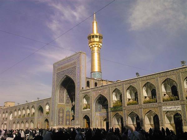 Pilgrims in Mashad shrine courtyard, golden minaret and tiled portals