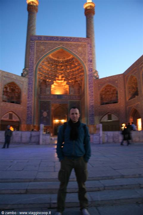 Traveler standing before the illuminated Shah Mosque in Esfahan at dusk