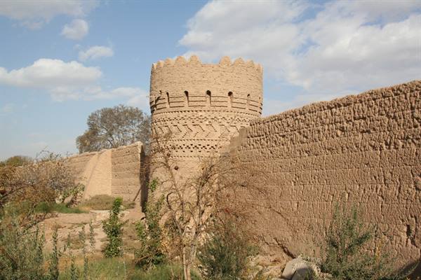 Mud brick tower and walls in Yazd under a blue sky