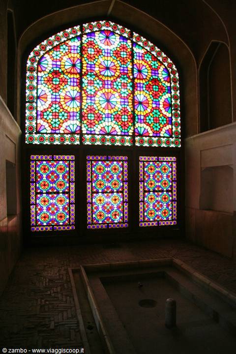 Stained glass windows light an interior room with pool, Yazd