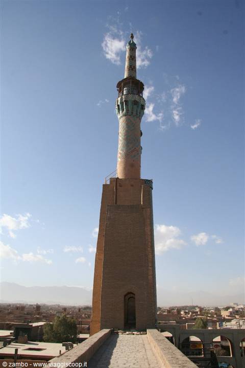 Brick and turquoise-tiled minaret rising above Yazd rooftops