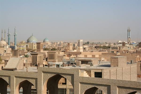 Yazd brick rooftops with windcatchers, domes and minarets under dusty haze