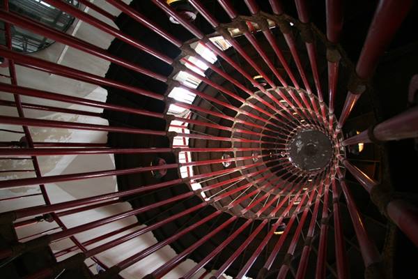 Red spiral railing seen from below, metal bars against the light