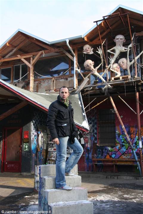Man standing on concrete blocks in front of Metelkova's sculptures, Ljubljana