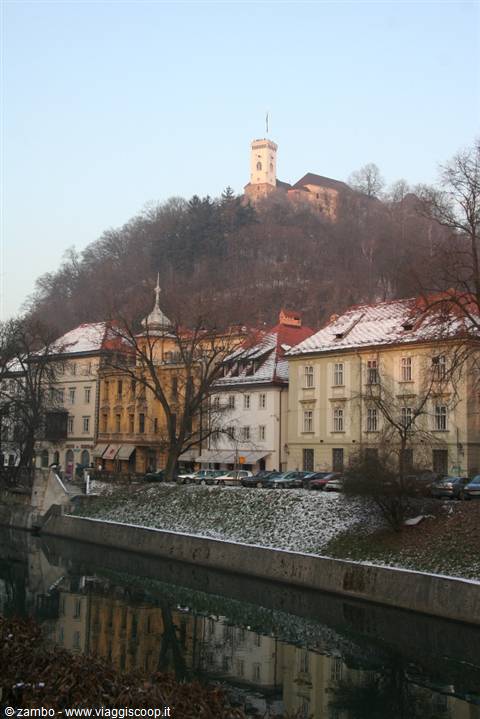 Ljubljana Castle on the snowy hill above riverside buildings