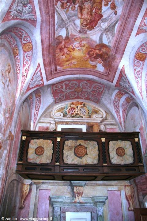 Carved wooden choir loft beneath a pink frescoed vaulted church ceiling
