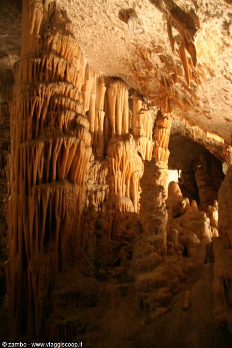 Limestone stalactite columns glowing under warm light inside a cave