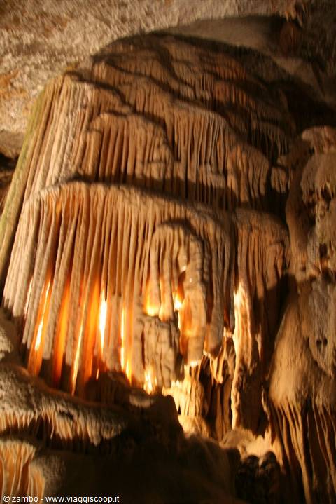 Limestone stalactite columns glowing orange inside a cave