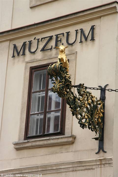 Gilded ram sign with green wrought iron on the Muzeum facade