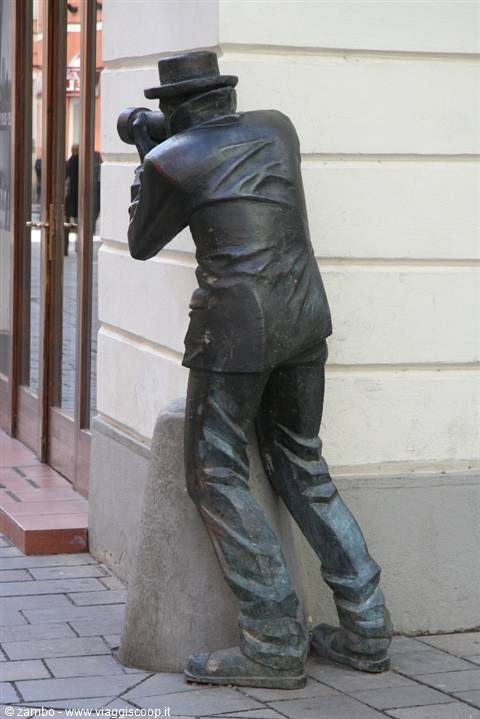 Bronze statue of a photographer in a hat taking pictures by a shop