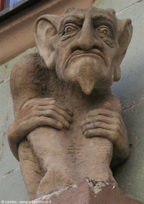 Stone statue of a grotesque horned demon with big ears on a facade