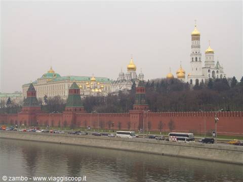 Red Kremlin walls and golden domes above the Moskva River with traffic