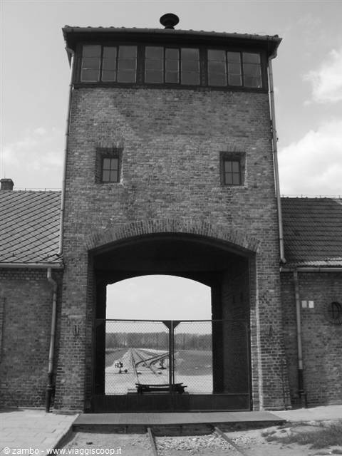 Brick guard tower over the Birkenau gate, railway tracks beyond the closed gate