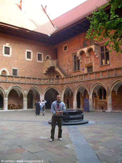 Man standing in the arcaded brick courtyard of Collegium Maius, Kraków