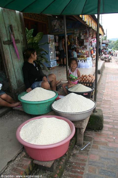 Woman and child beside basins of white rice under a green umbrella
