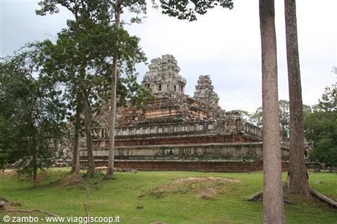Stone temple tower rising among tall trees and green lawn, Angkor