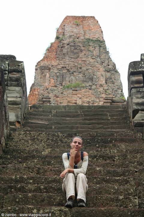 Woman seated on stone steps of a ruined Khmer temple, soft daylight