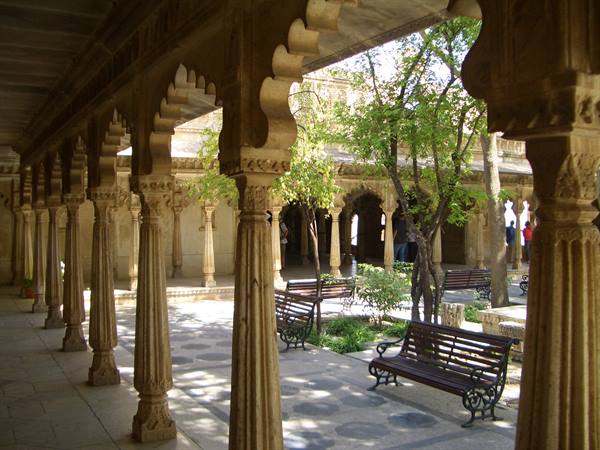 Sandstone carved colonnade surrounding a courtyard with benches and trees