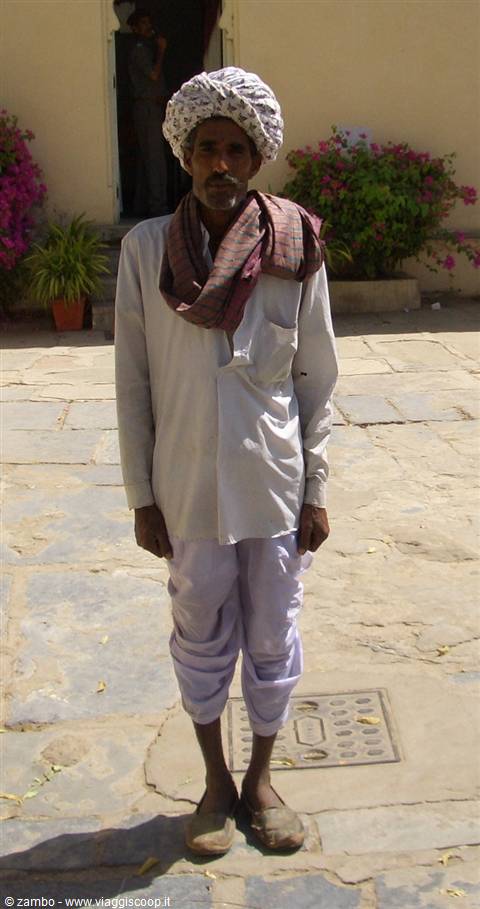 Man in white turban and red scarf posing on stone pavement