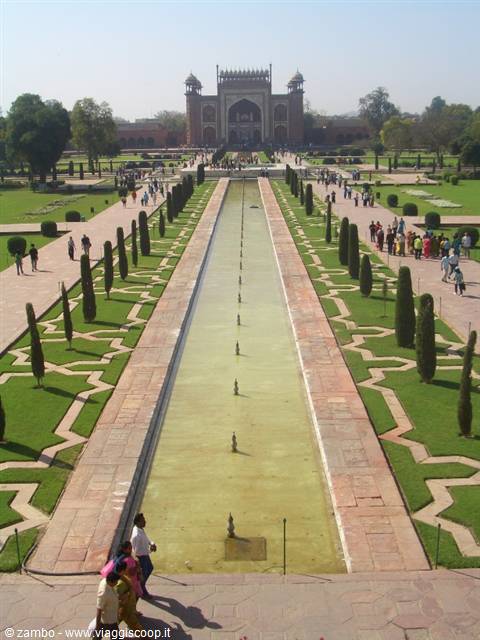 Long water channel with fountains in Taj Mahal gardens, visitors under sunlight