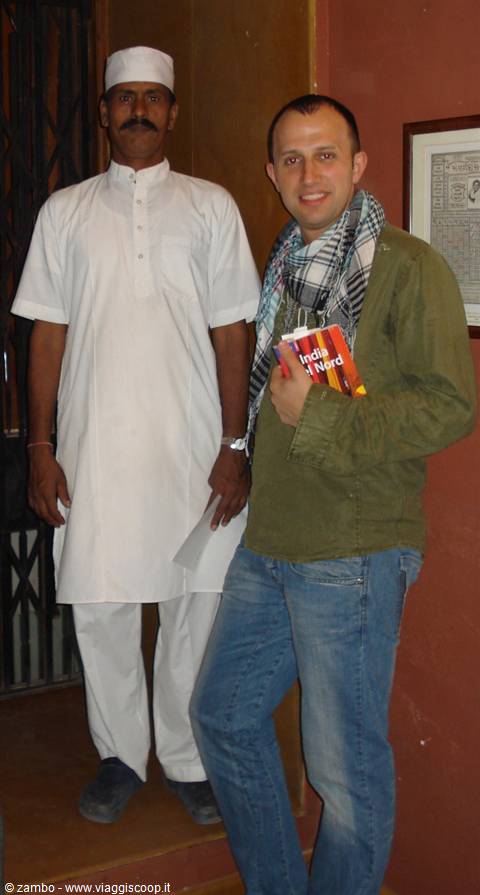 Tourist holding Lonely Planet guide next to man in white Indian kurta