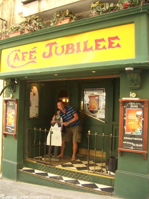 Smiling man at Café Jubilee entrance, yellow sign, checkered floor